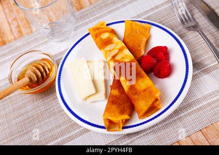 Crepes sottile con fette di brie morbido, miele e lamponi Foto Stock