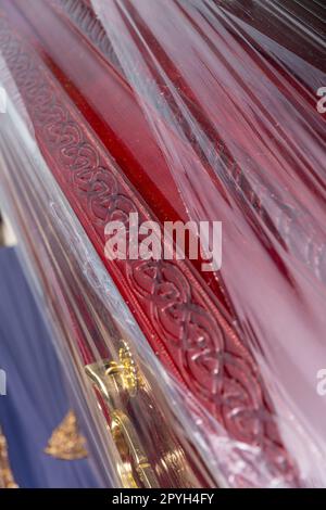Nuova bara in legno con manico in metallo giallo, confezionata in involucro di plastica in un negozio di articoli funerari. Negozio di vendita di bare, corone funebri e volate Foto Stock