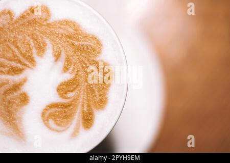 Delizioso caffè cappuccino in tazza latte di vetro con panna acida schiuma di latte con spike su piastra in ceramica bianca Foto Stock