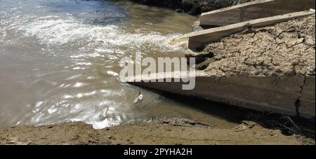 Un grande drenaggio cittadino drena le acque reflue in un canale che confluisce nel fiume. Problema ecologico. Il concetto di protezione ambientale ed ecologia. Struttura in calcestruzzo Foto Stock