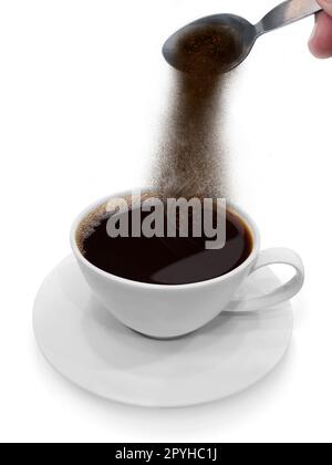 La mano versa il caffè istantaneo da un cucchiaio in una tazza da caffè Foto Stock