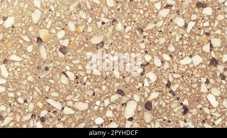 Superficie in calcestruzzo con macchie multicolore di piccole pietre. Tono beige o arancione. Parete di un edificio o lastra di cemento. Primo piano. Superficie in cemento macchiato. Decorazioni interne o esterne Foto Stock