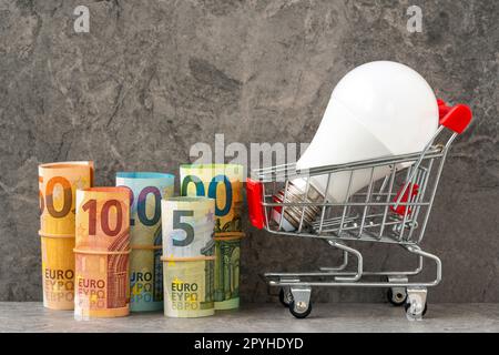 Lampadina nel carrello accanto ai rotoli di denaro Euro Foto Stock