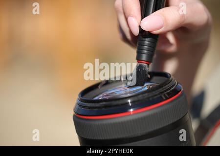 Fotografo che pulisce le mani l'obiettivo esterno Foto Stock