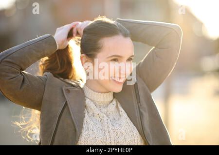 Donna felice che prepara la coda di pony al tramonto Foto Stock