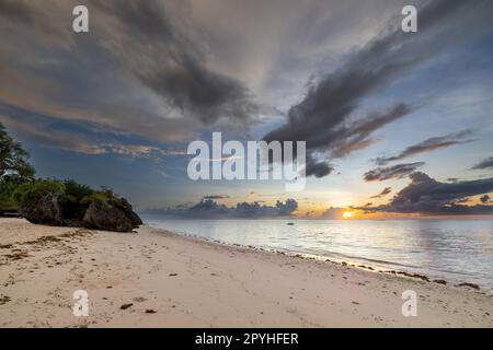 Questa foto mozzafiato cattura la bellezza di un'alba sulla spiaggia di Diani in Kenya. Le vivaci tonalità arancio e giallo dei raggi del sole illuminano Foto Stock