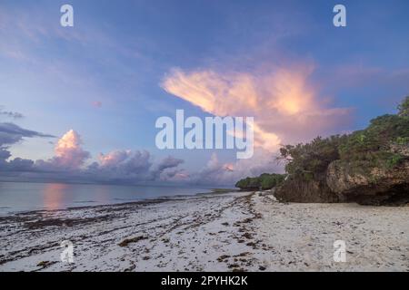 Questa foto mozzafiato cattura la bellezza di un'alba sulla spiaggia di Diani in Kenya. Le vivaci tonalità arancio e giallo dei raggi del sole illuminano Foto Stock