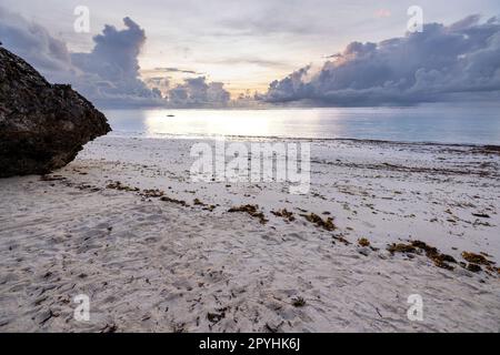 Questa foto mozzafiato cattura la bellezza di un'alba sulla spiaggia di Diani in Kenya. Le vivaci tonalità arancio e giallo dei raggi del sole illuminano Foto Stock