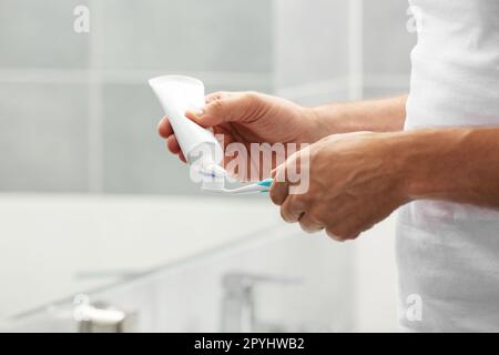 Uomo che applica dentifricio su pennello in bagno, primo piano Foto Stock