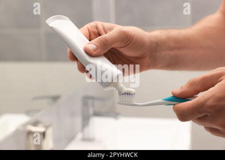 Uomo che applica dentifricio su pennello in bagno, primo piano Foto Stock