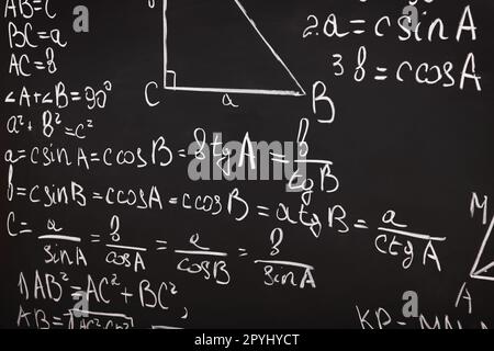 Diverse formule matematiche scritte con il gesso sulla lavagna Foto Stock