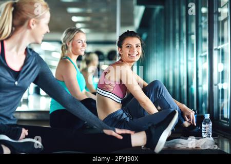 La palestra è migliore con gli amici. tre giovani donne attraenti che fanno una pausa durante il loro allenamento in palestra. Foto Stock