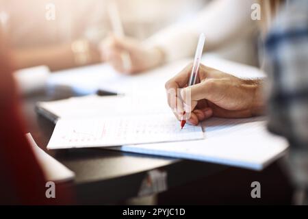 Per andare avanti con i loro studi. Primo piano degli studenti universitari che lavorano nella biblioteca del campus. Foto Stock