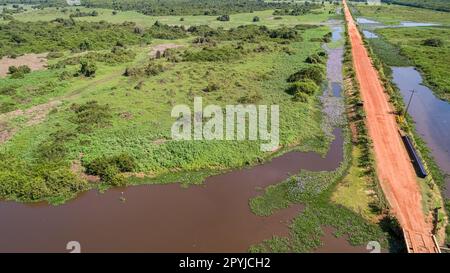 Veduta aerea della strada sterrata di Transpantaneira accanto ad una laguna fangosa nel tipico paesaggio delle paludi del Nord Pantanal, Mato Grosso, Brasile Foto Stock