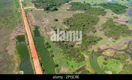 Veduta aerea della strada sterrata di Transpantaneira con lagune a destra e a sinistra, attraversando il tipico paesaggio delle paludi del Nord Pantanal, Mato Grosso, Brasile Foto Stock