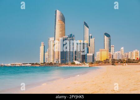 Vista panoramica della splendida spiaggia di sabbia vicino all'argine lungomare Corniche, con una splendida vista al tramonto di Abu Dhabi, i torreggianti grattacieli degli Emirati Arabi Uniti Foto Stock