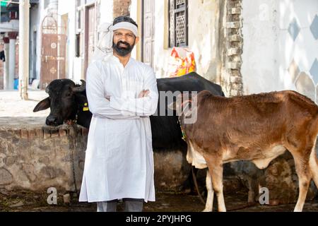 Ritratto di giovani bovini maschi indian allevatori in piedi braccia incrociate, persone e animale vacca. Foto Stock