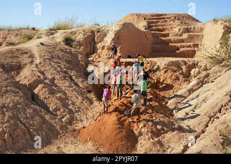 Ilakaka, Madagascar - 30 aprile 2019: Gruppo di uomini malgasci sconosciuti che estraggono zaffiro in miniera di superficie, muovendo terreno con pale in una giornata di sole. THI Foto Stock