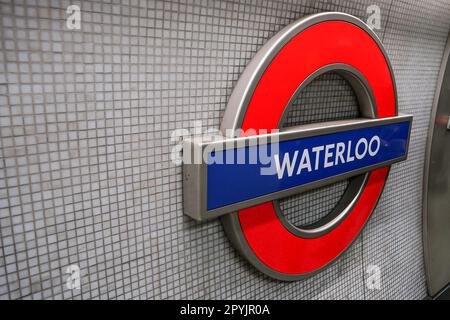 Londra, Regno Unito - 02 febbraio 2019: Cartello illuminato della stazione della metropolitana di Waterloo alla parete della fermata della metropolitana. Design tradizionale rosso, bianco e blu Foto Stock