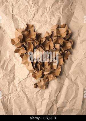 Forma a cuore realizzata con materiale di imballaggio di carta riciclata su carta riciclata frantumata Foto Stock