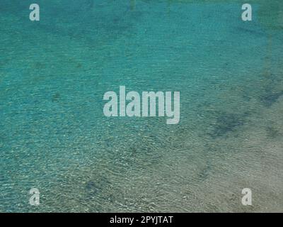 acqua blu e turchese. Acqua di mare limpida con onde e riflessi solari. Il fondo è visibile Foto Stock