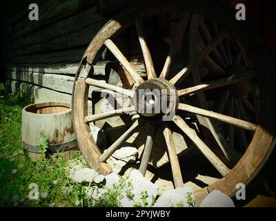 Ruota di legno da un carrello. Ruote decorative per decorare prati, esterni e interni rustici. Ruota fatta in casa contro il muro. Stile retrò o vintage. La vita in campagna Foto Stock