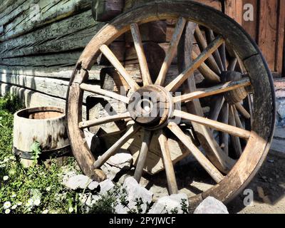 Ruota di legno da un carrello. Ruote decorative per decorare prati, esterni e interni rustici. Ruota fatta in casa contro il muro. Stile retrò o vintage. La vita in campagna Foto Stock