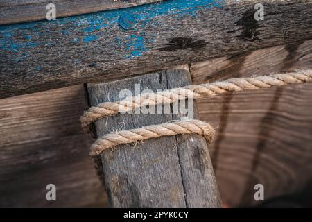 Semplice corda naturale legata intorno alla parte in legno della barca da pesca, dettaglio closeup Foto Stock