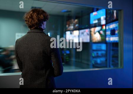 Uomo che guarda la riflessione dello schermo del computer nella finestra della stanza del server Foto Stock