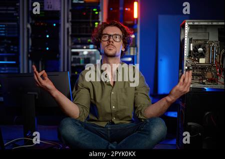 Un tecnico penoso che medita nella sala server del moderno data center Foto Stock