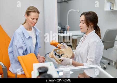 Ginecologo che mostra le ossa del bacino femminile e che dà la consultazione alla donna Foto Stock