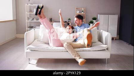 Coppia che salta sul divano a casa Foto Stock