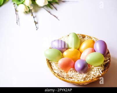 Uova di Pasqua colorate in un cestino. Bouquet di tulipani e rami di salice. Complimenti sfondo. Foto Stock