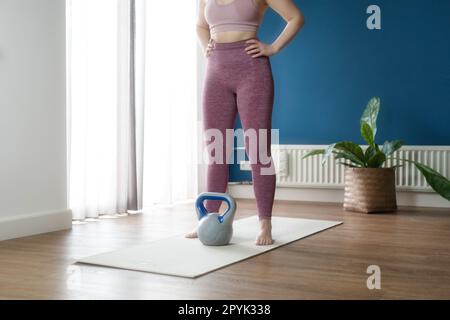 Bella ragazza sport a casa . Esercizio di fitness con kettlebell, allenamento intelligente, esercizio fisico, allenamento domestico Foto Stock