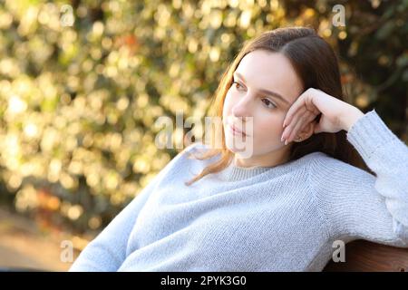 Donna pensiva che contempla di sedersi su una panchina Foto Stock