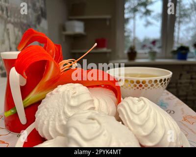 qualche marshmallow su un piattino e una tazza di tè profumato Foto Stock