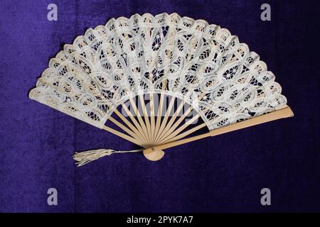 Ventilatore a mano in pizzo vintage su sfondo viola in velluto Foto Stock