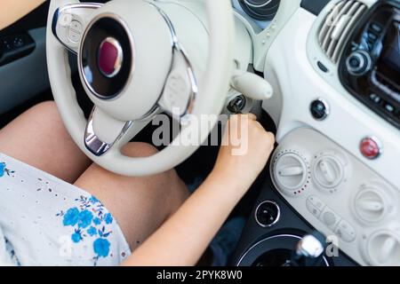 Mano del conducente femmina che inserisce la chiave dell'auto e avvia il primo piano del motore Foto Stock