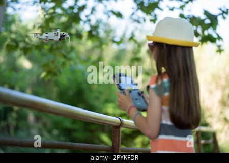 Bambina che vola un piccolo drone nel parco con un telecomando Foto Stock