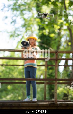 Bambina che vola un piccolo drone nel parco con un telecomando Foto Stock