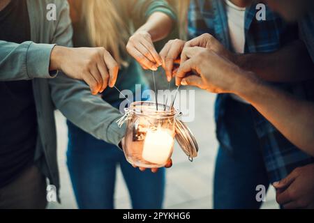 Stavano andando illuminare il mondo insieme. un gruppo di persone irriconoscibili mani di illuminazione in su scintillanti insieme all'esterno. Foto Stock