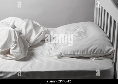 Letto non fatto in casa, lenzuola bianche in raso, letto bianco, cuscino e coperta Foto Stock