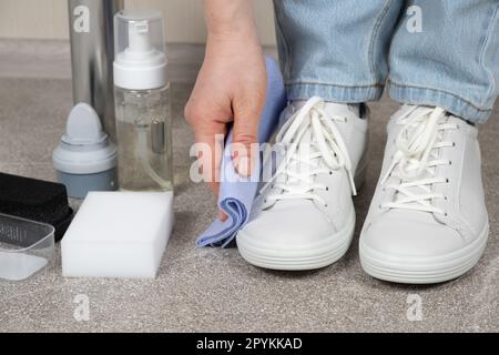 Una donna pulisce le sneaker in pelle bianca con uno straccio, rimuove la  polvere Foto stock - Alamy