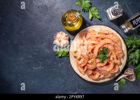 Dieta di cottura sfondo bianco di carne di pollame. Strisce di pollo fresche a fette crude per la cottura, con spezie, erbe aromatiche, su uno sfondo di cemento nero vista dall'alto c Foto Stock