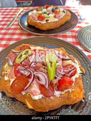 Langos, pizza ungherese su piatto, fritto, con formaggio grattugiato, panna acida, pancetta, salame, cipolla e prezzemolo Foto Stock