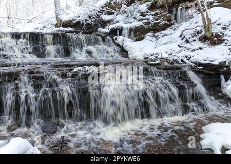 Piccola cascata Vasaristi in inverno, parco nazionale di Lahemaa, Estonia. Esposizione lunga Foto Stock