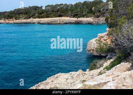 Cala Mondrago è una spiaggia di villeggiatura appartata a Maiorca con acque calme protette da promontori circostanti Foto Stock