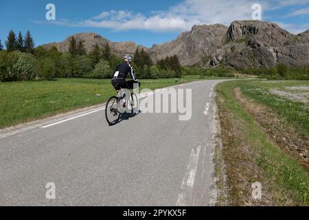 Ciclista strada maschile sulle strade tranquille di Leka Island, Norvegia. Foto Stock