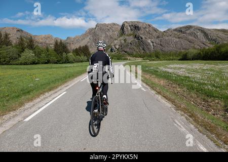 Ciclista strada maschile sulle strade tranquille di Leka Island, Norvegia. Foto Stock