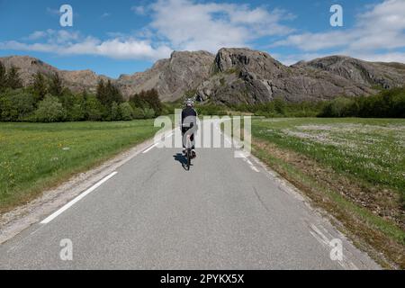 Ciclista strada maschile sulle strade tranquille di Leka Island, Norvegia. Foto Stock